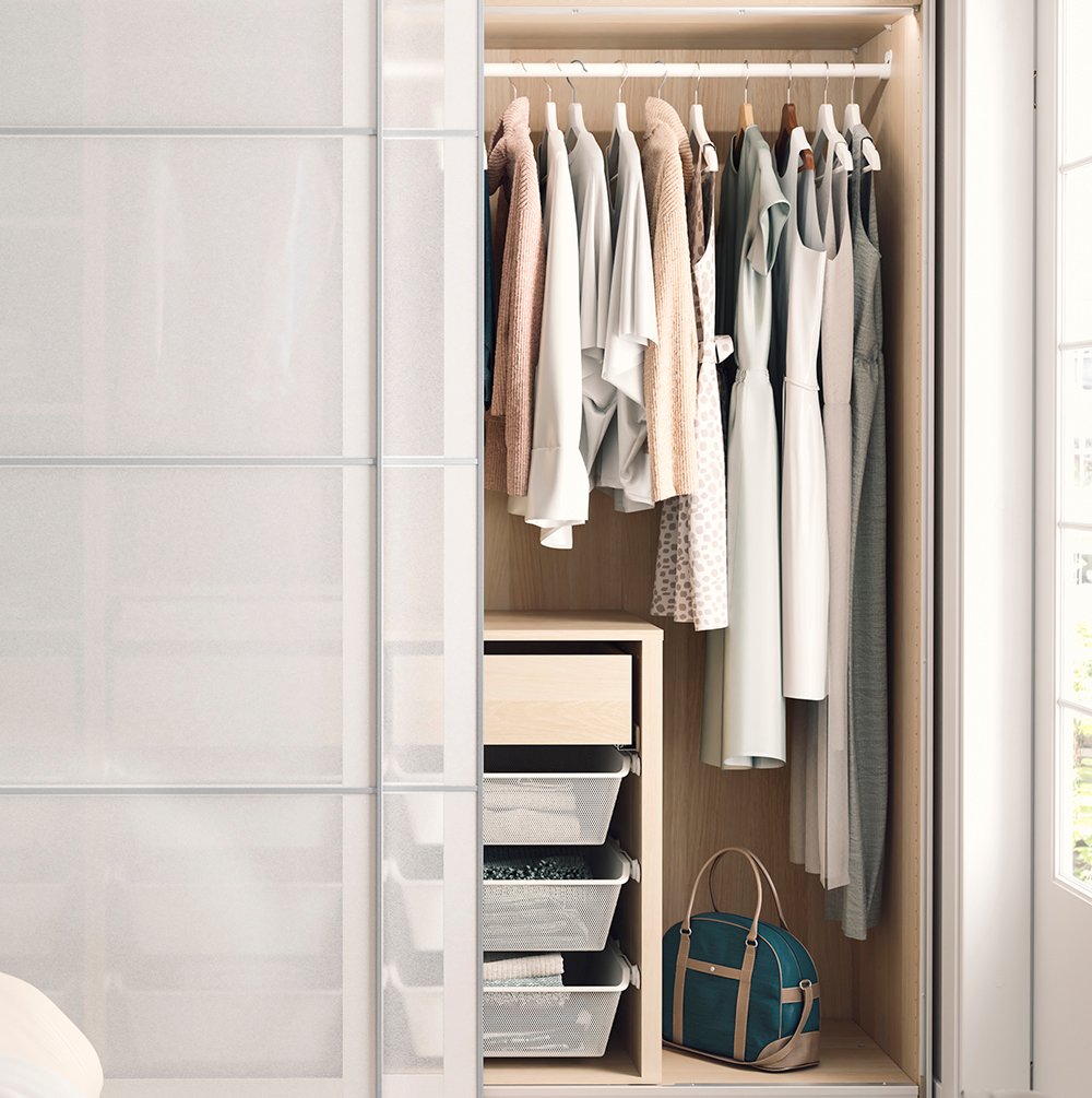 En garderob med ljusa skjutdörrar. Garderoben är delvis öppen och visar kläder i prydlig stil.