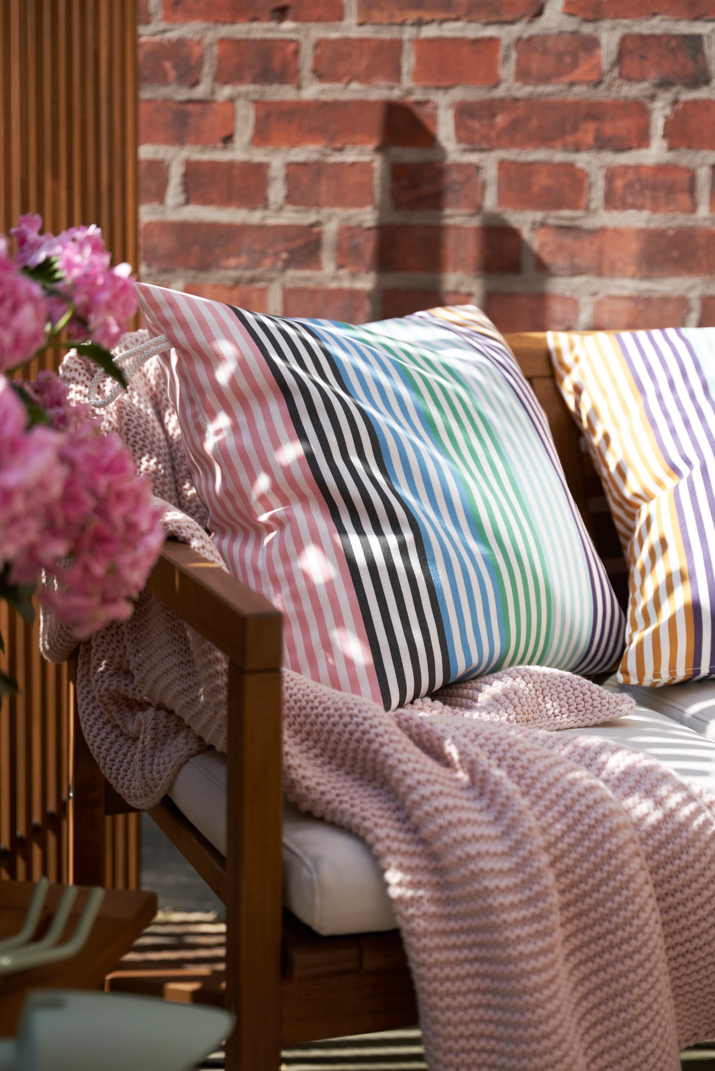 Närbild på randiga kuddar i rosa, grönt och gult.