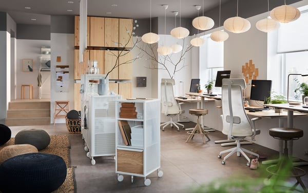 Una planta de oficina abierta con espacios para trabajar y descansar. Se observa una serie de muebles de almacenaje con ruedas.