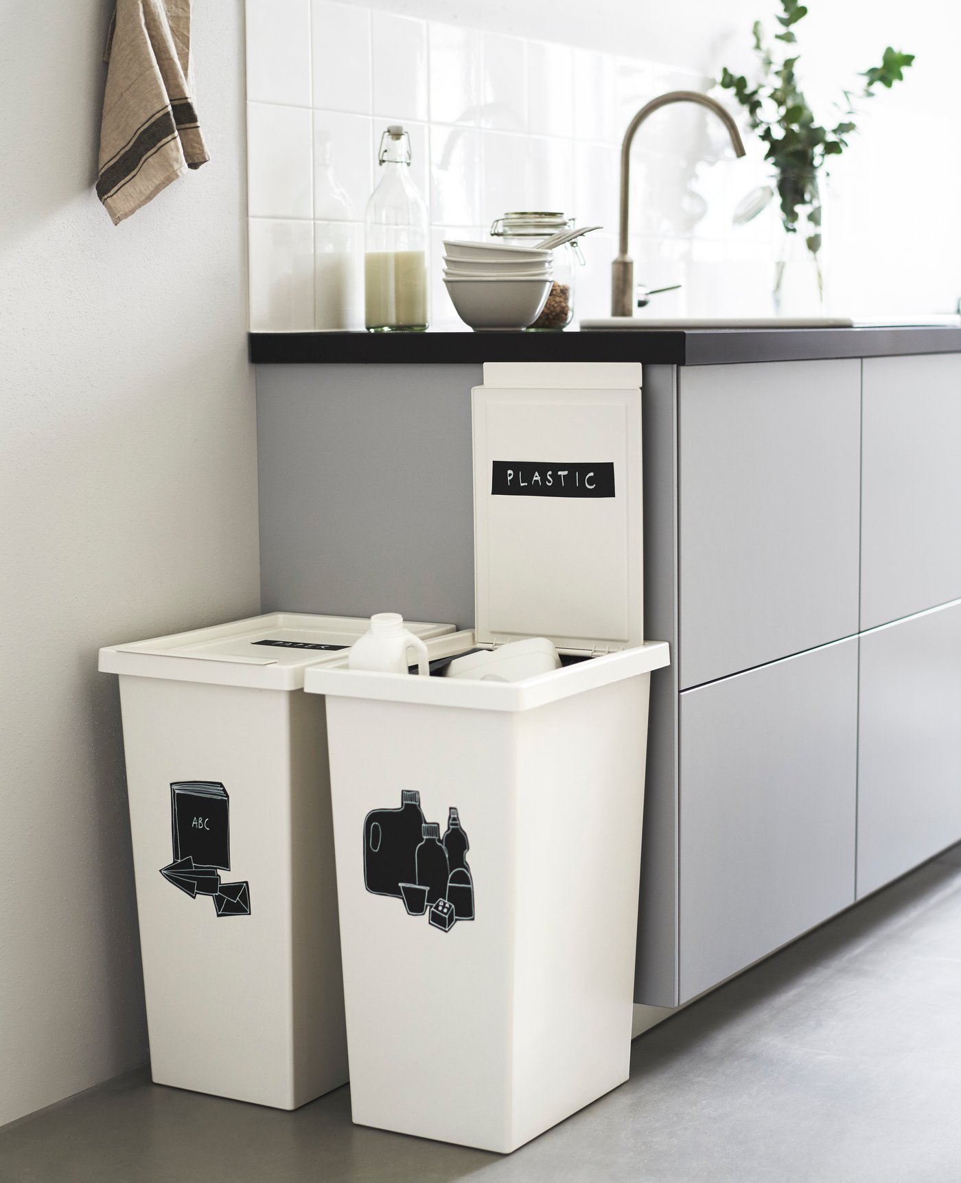 Due contenitori bianchi FILUR posti accanto ad una cucina con ante grige e piano nero.