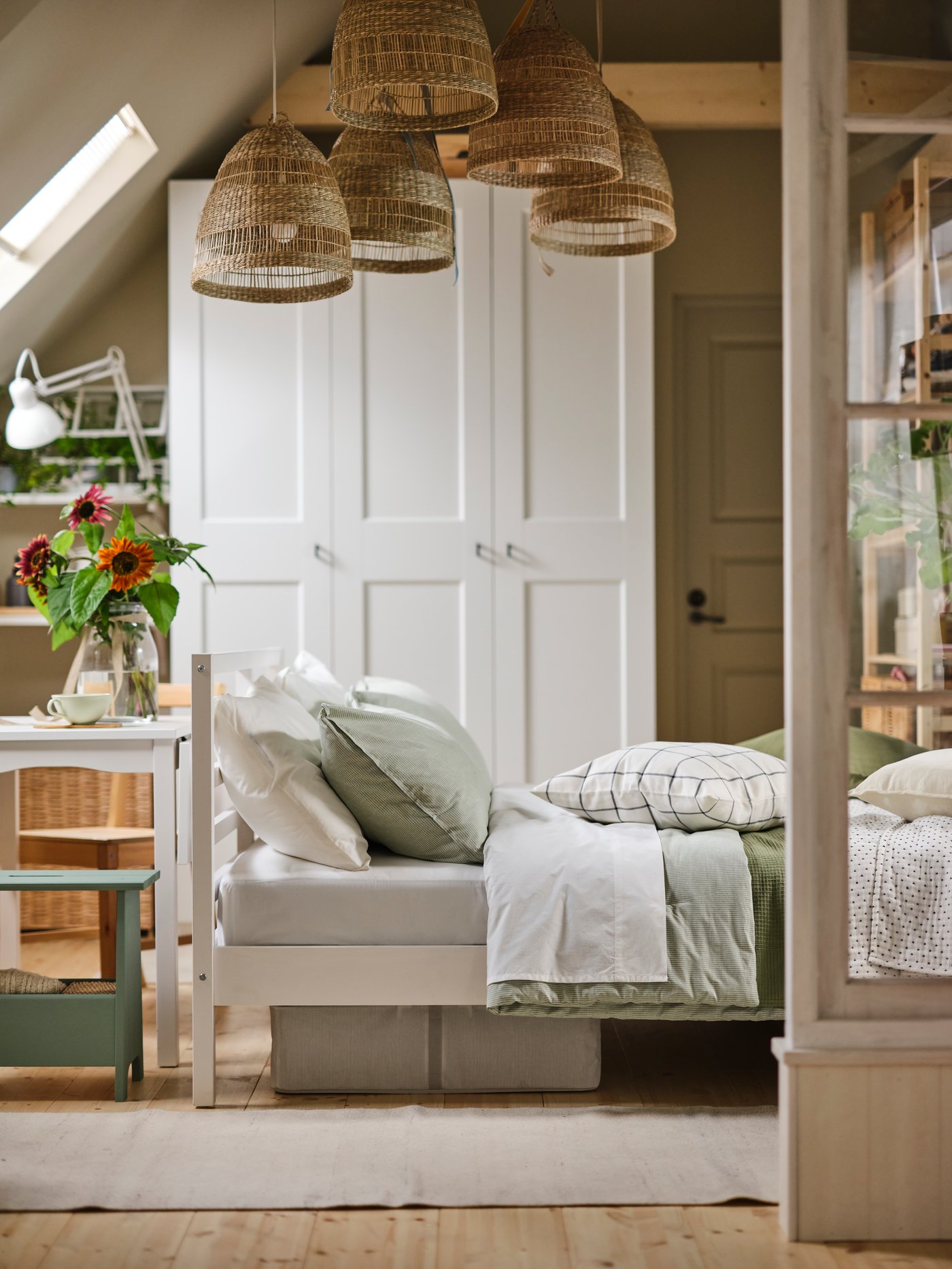 A white TARVA bed in a rustic bedroom with five sedge pendant lampshades above it, in front of a white wardrobe with 6 doors.