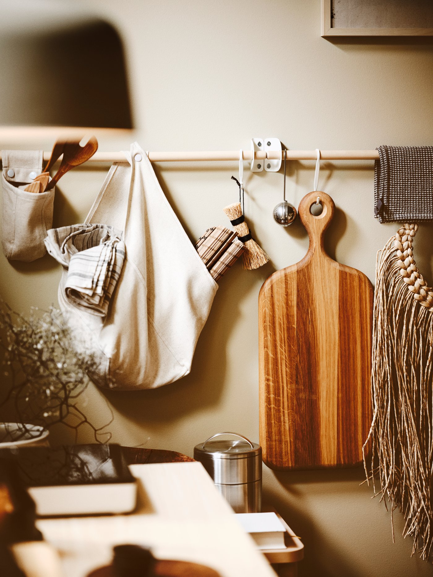A kitchen with an ARTISTISK chopping board, cooking utensils, kitchenware and a tea infuser hung from rails.