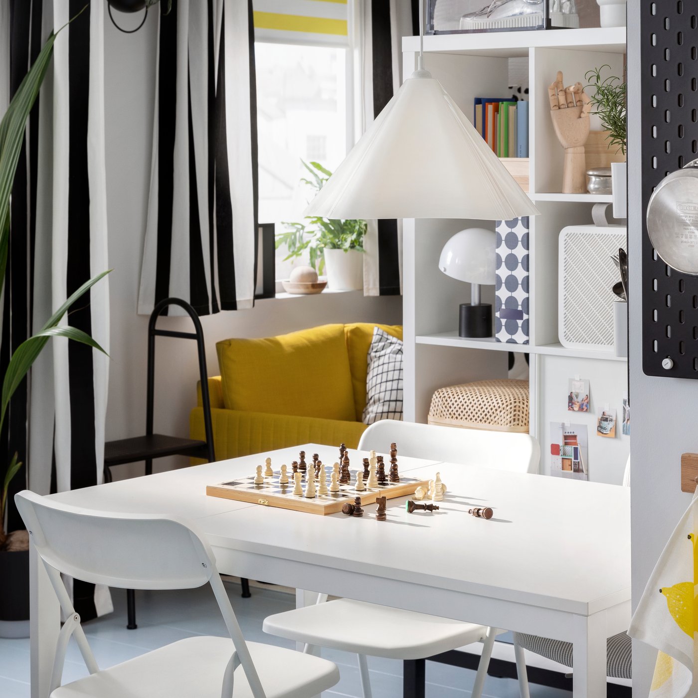 Ein VIHALS Ausziehtisch und VIHALS Klappstühle stehen in einem kleinen Essbereich unter einer weißen ZEBRASÄV Hängeleuchte.