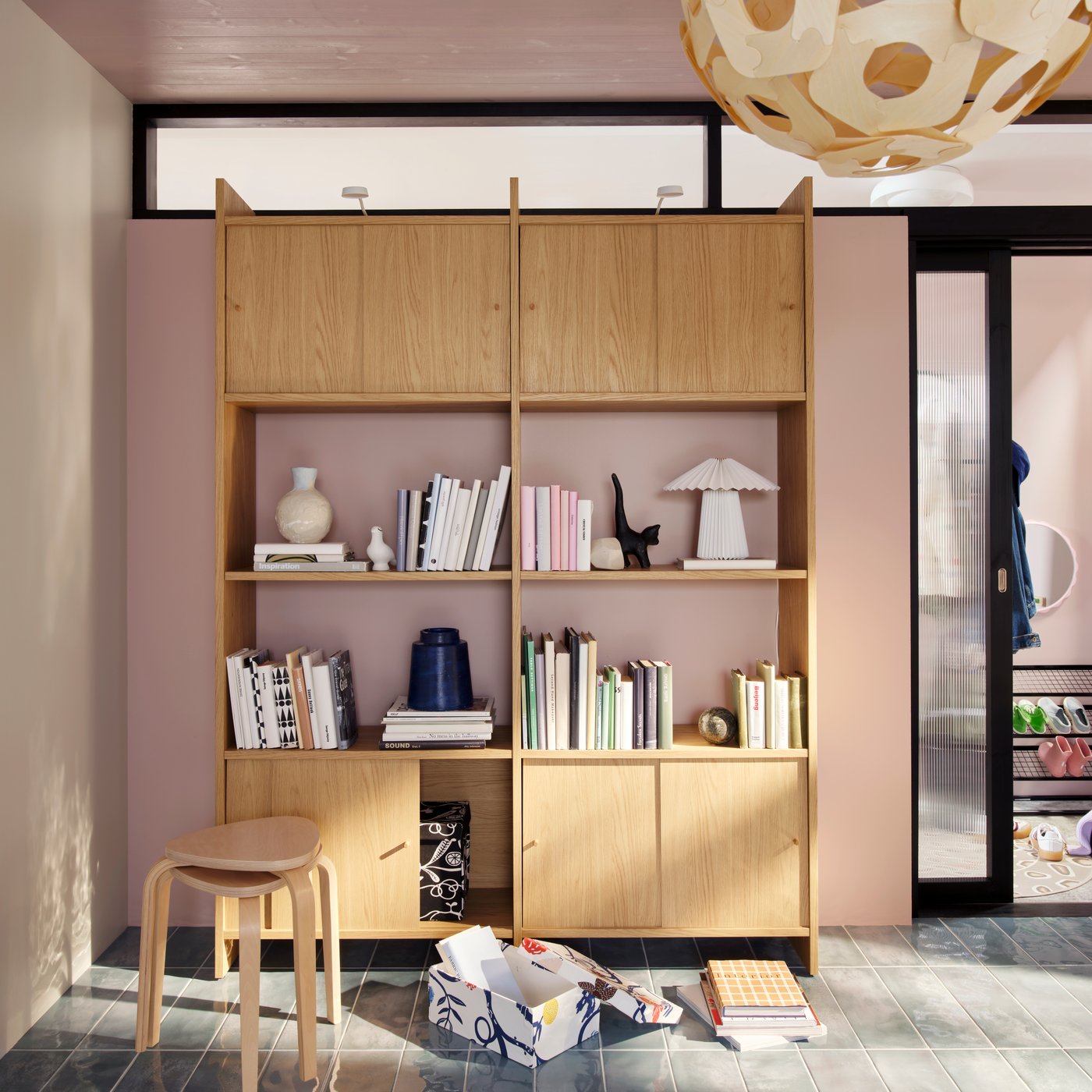A bright living room with a LÅDMAKARE storage combination with books and decoration, stacked KYRRE stools beside it.