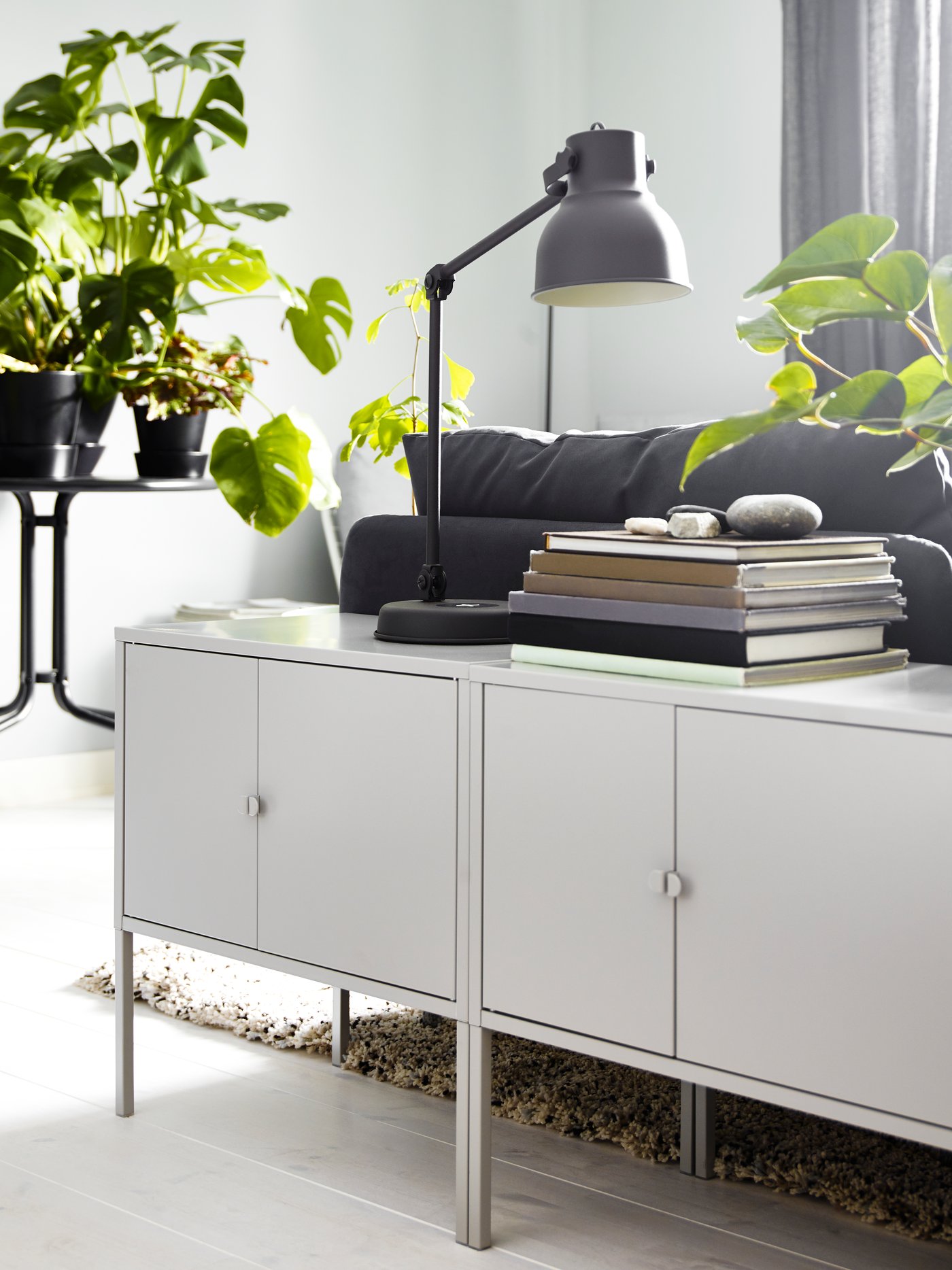 LIXHULT cabinets in the living room with a HEKTAR table lamp behind a SODERHAMN dark grey sofa.  