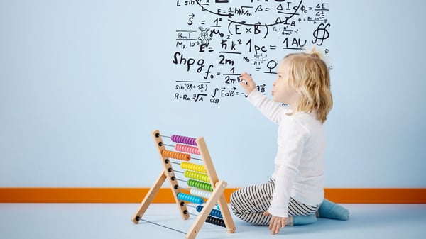 子どもが壁に英数字を書いており、隣にイケアのおもちゃがある