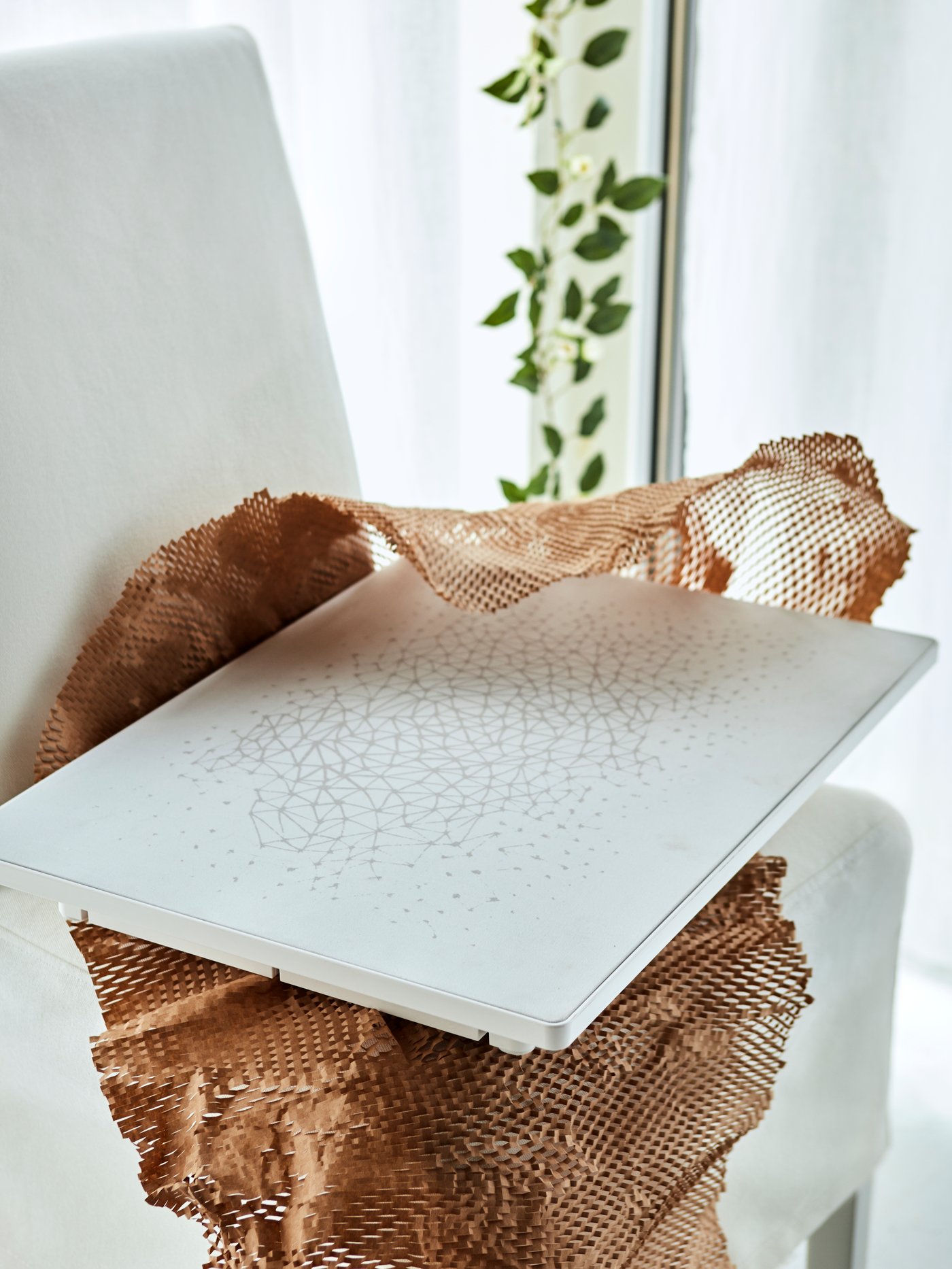 Un panel SYMFONISK en blanco con un estampado abstracto gráfico sobre una silla de tela.