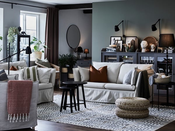 Traditional deco style room with two cream sofas, dark walls and black, wooden and rattan home accessories and furniture.