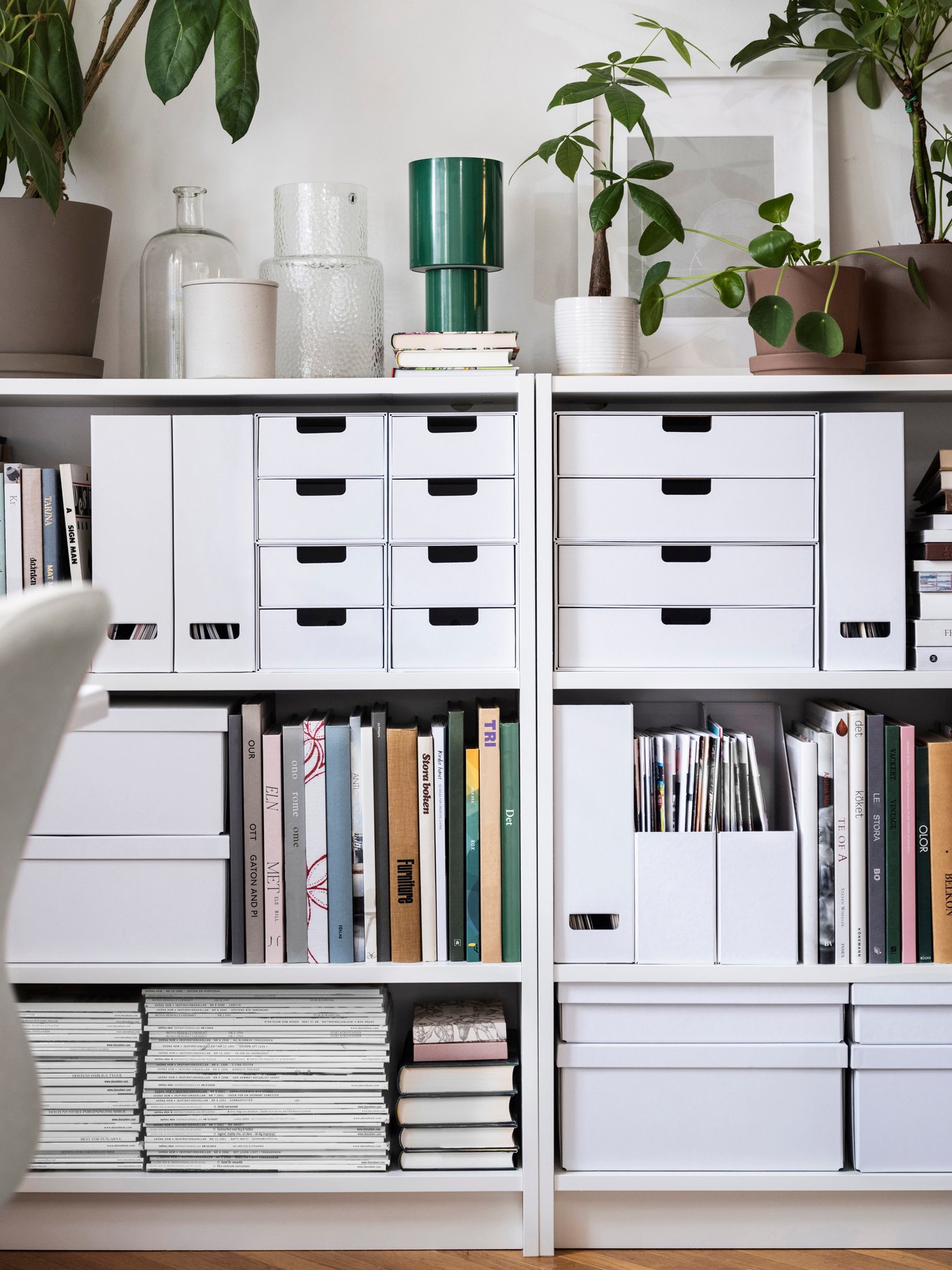 White FJÄDERHARV storage boxes with lid, magazine files and mini chests with 2 drawers stand in bookcases against a wall.