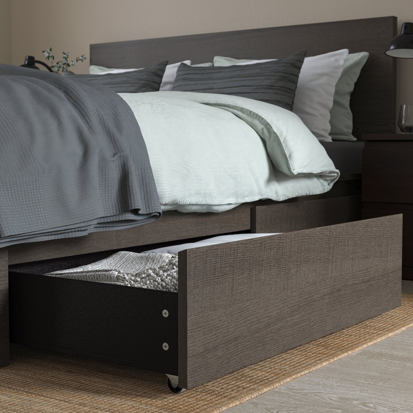 Dark wood bed with an open storage drawer beneath, filled with neatly folded bedding.