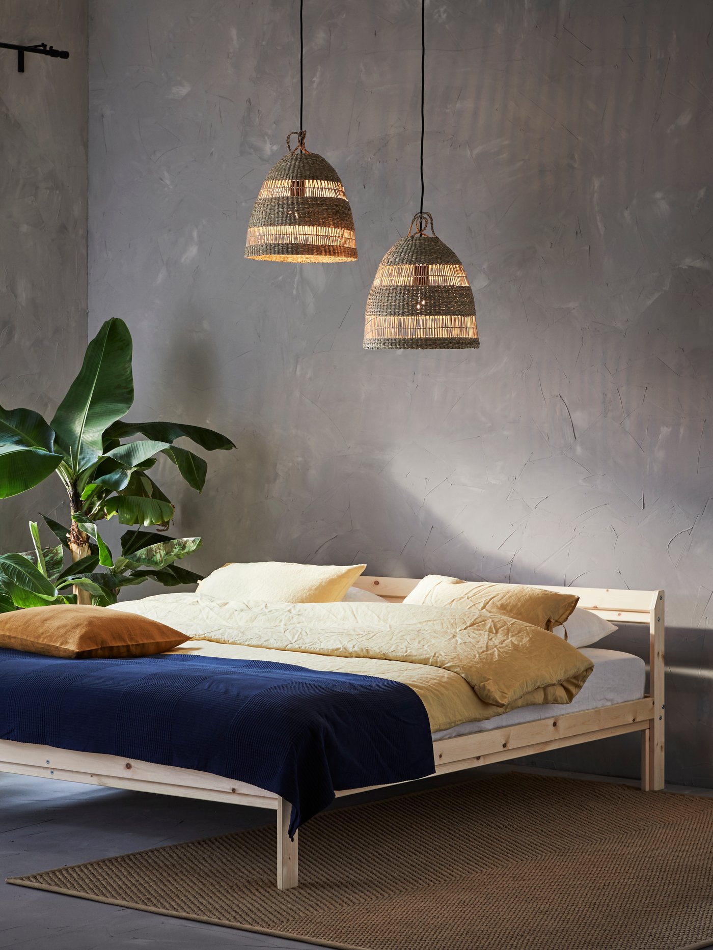 Dormitorio con somier, funda de duvet y fundas de almohada, fundas de cojín, verde planta de interior, colgante lámpara cortinas, colcha, alfombra.