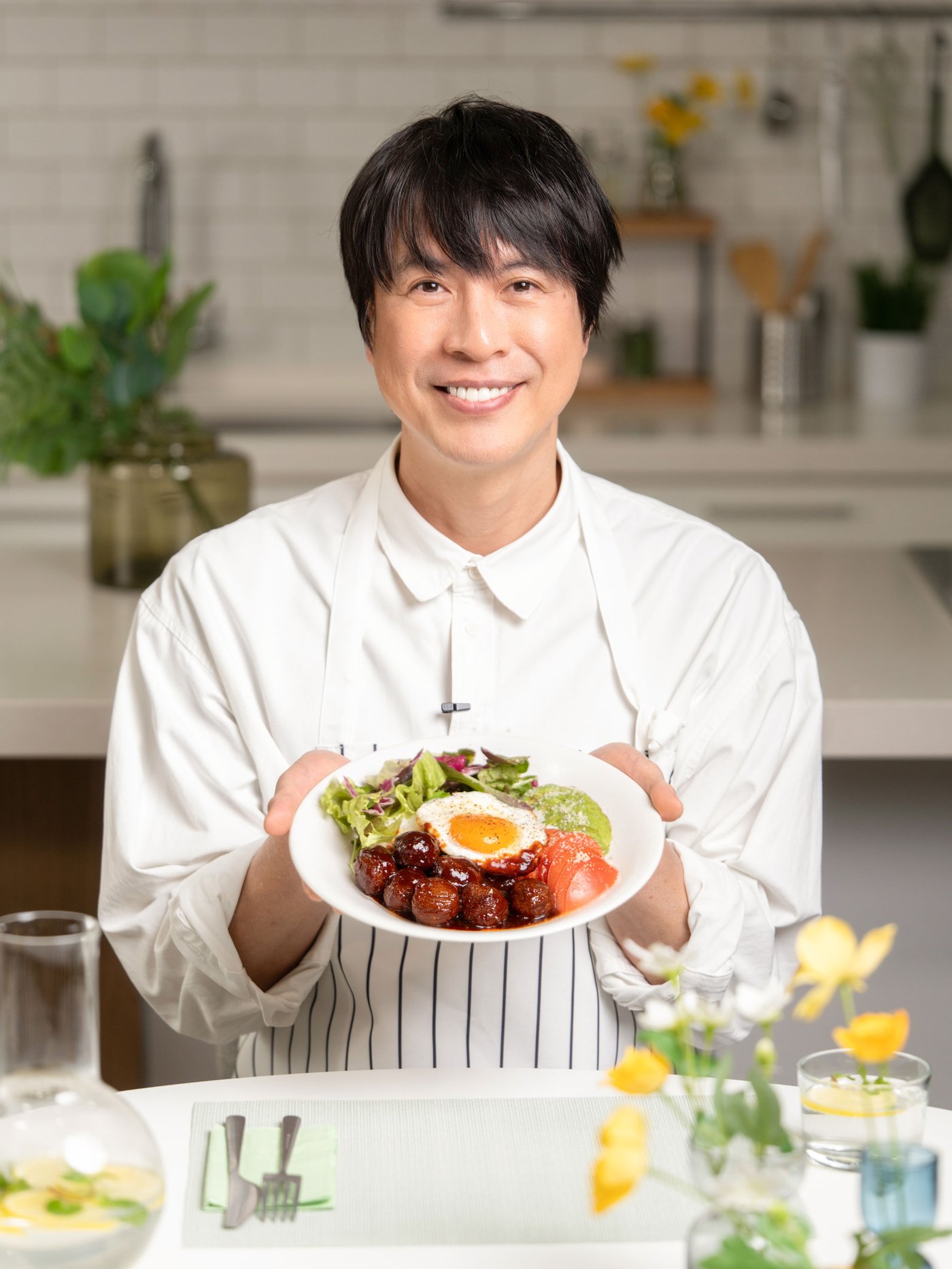 料理研究家・コウケンテツさんが、とろ～り卵のロコモコをテーブルで手に持つ。