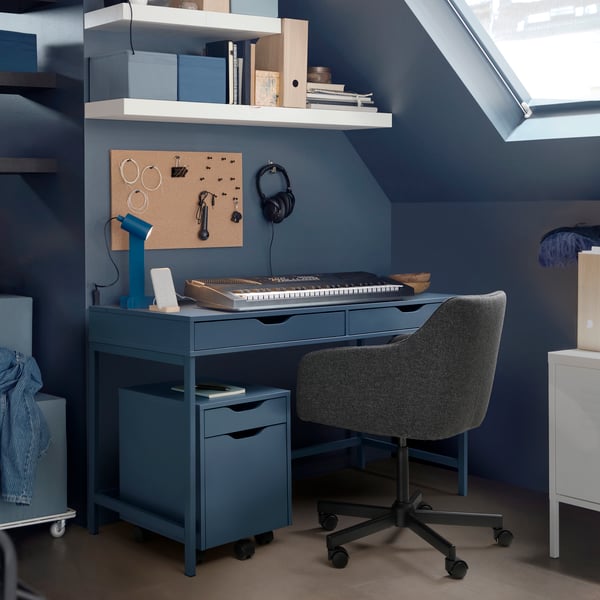 A black-blue ALEX desk, with a separate drawer unit and a swivel chair sitting in front and a keyboard on top.