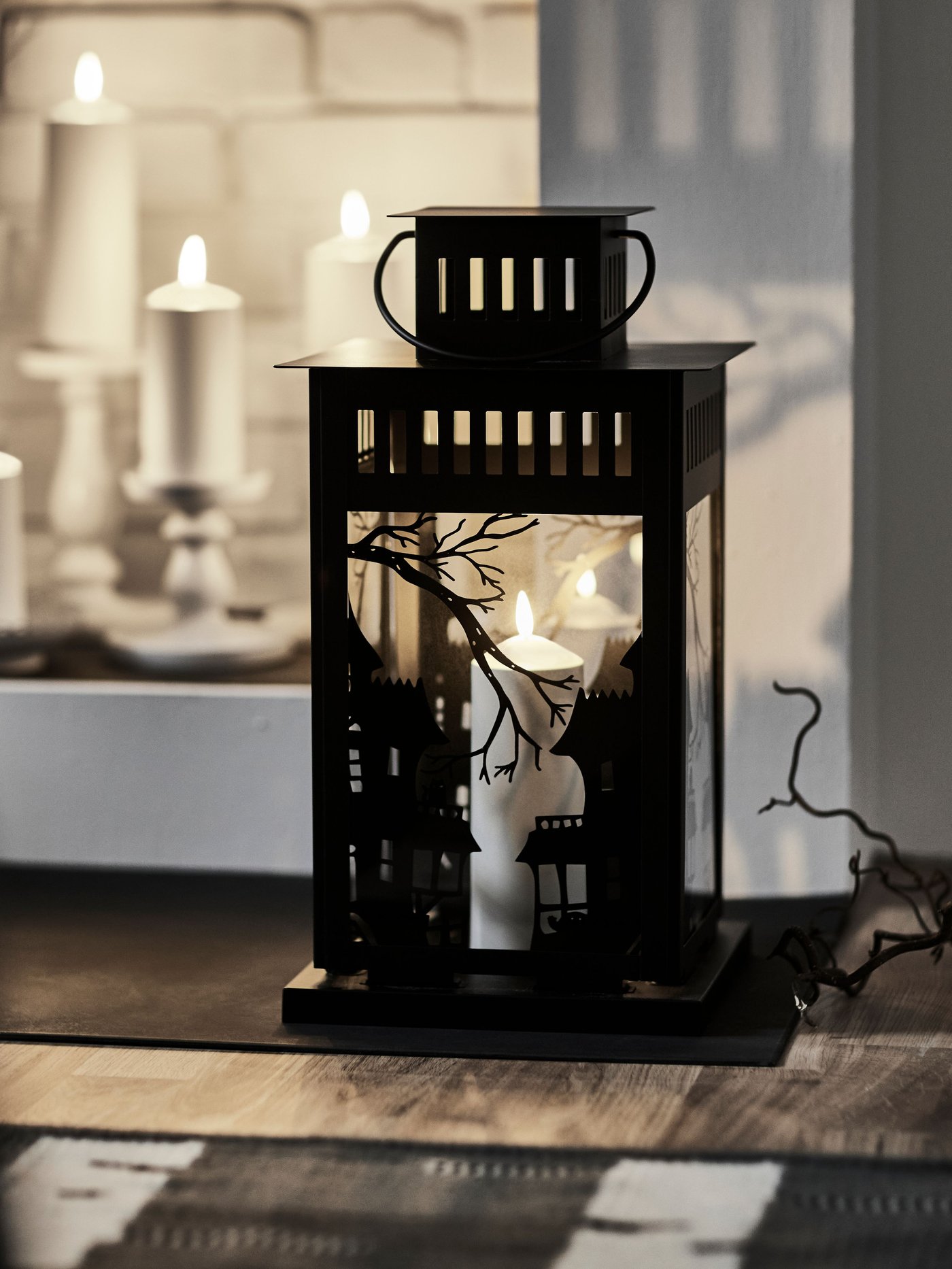 A black KUSTFYR lantern for pillar candle, in/out