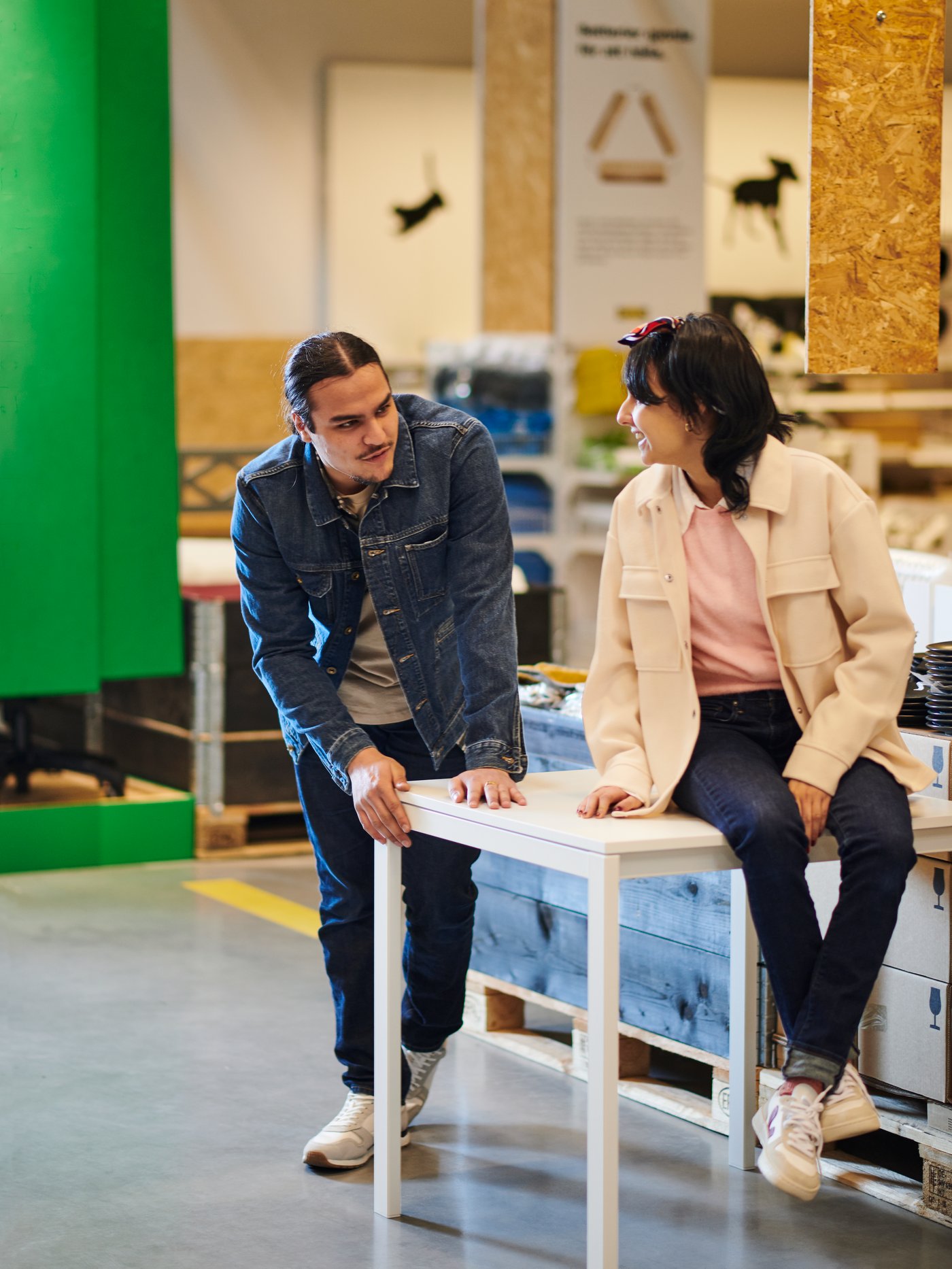 Konieta siedząca na białym stole w dziale Okazji na Okrągło. Mężczyzna opiera się i pochyla nad stołem