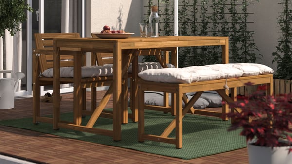 A NÄMMARÖ outdoor dining table with matching chairs and a bench is placed on a dark green MORUM outdoor rug.