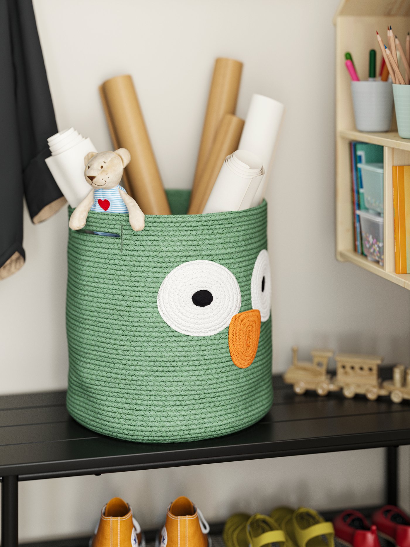 Close-up of a green UPPSTÅ storage bag on top of a bench, full of toys, rolls of paper and little FABLER BJÖRN on top.