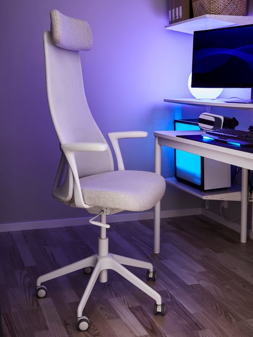 Spațiu de lucru cu un scaun de birou bej cu brațe, o masă dreptunghiulară, o lampă aprinsă și un monitor de computer.
