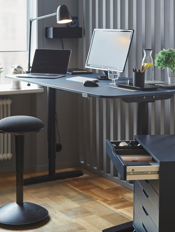 A home office setting featuring a blue BEKANT tabletop stand sit desk  with an ALEX drawer.