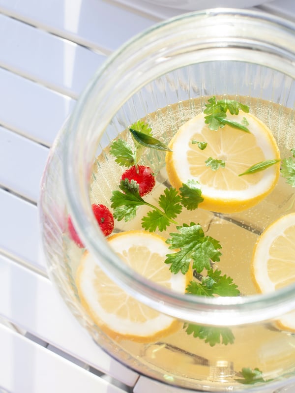 Midsummer drink with citrus fruits served in a glass container.