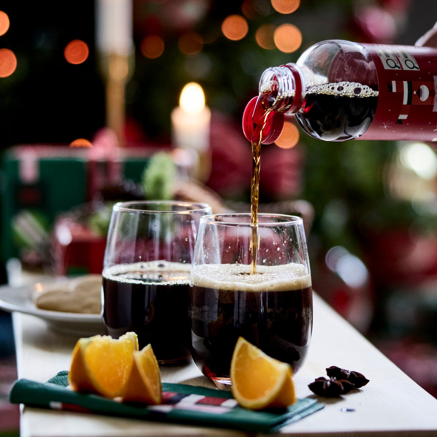 Two small, clear glasses sitting on coffee table. Holiday beverage being poured into glasses.