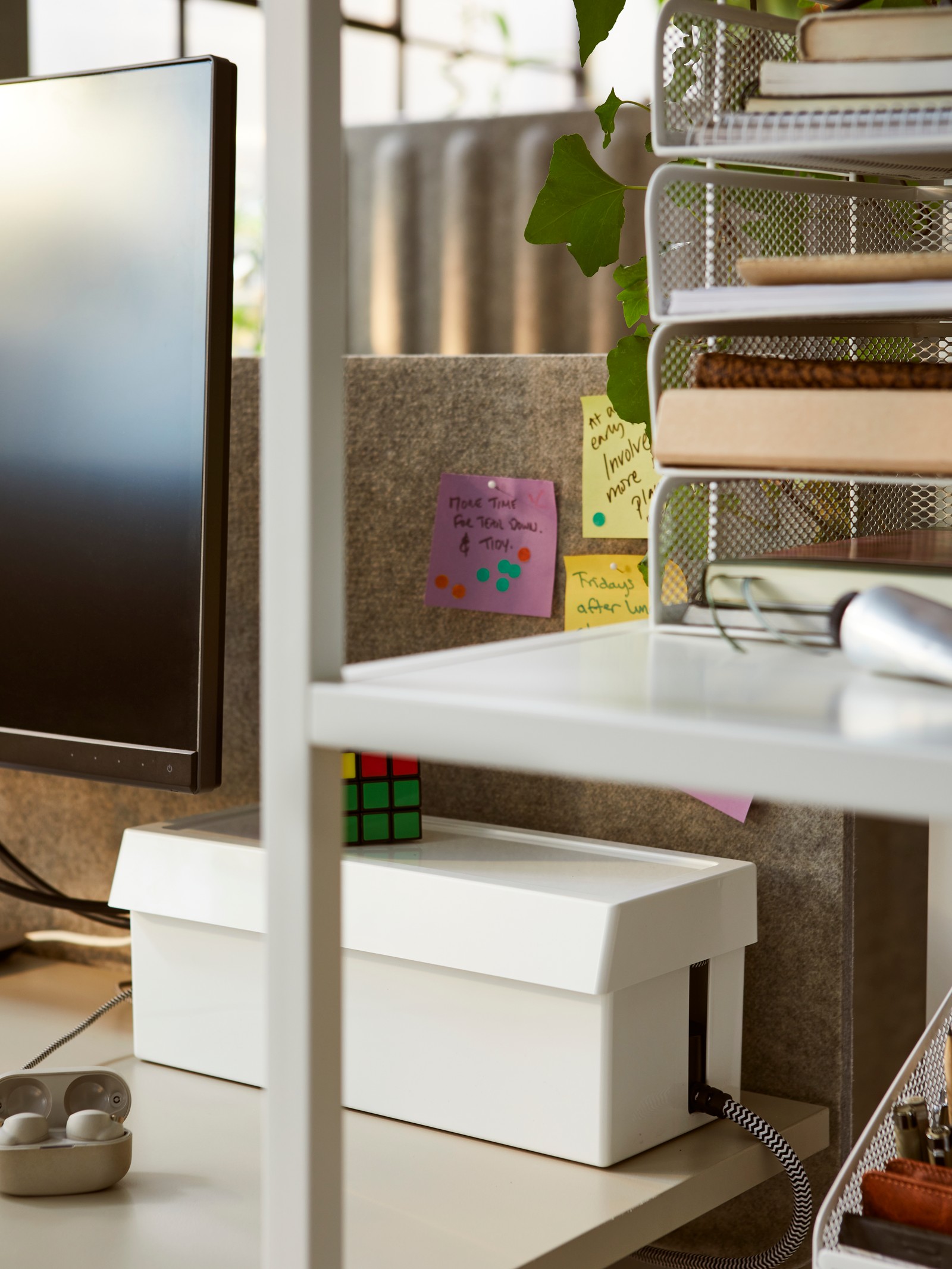 Una caja de cables blanca escondida detrás de una pantalla de monitor con un cordón colgando