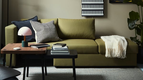 Mörk LINDÅKRA bäddsoffa med raka linjer och dekorationskuddar i stilren inredning.