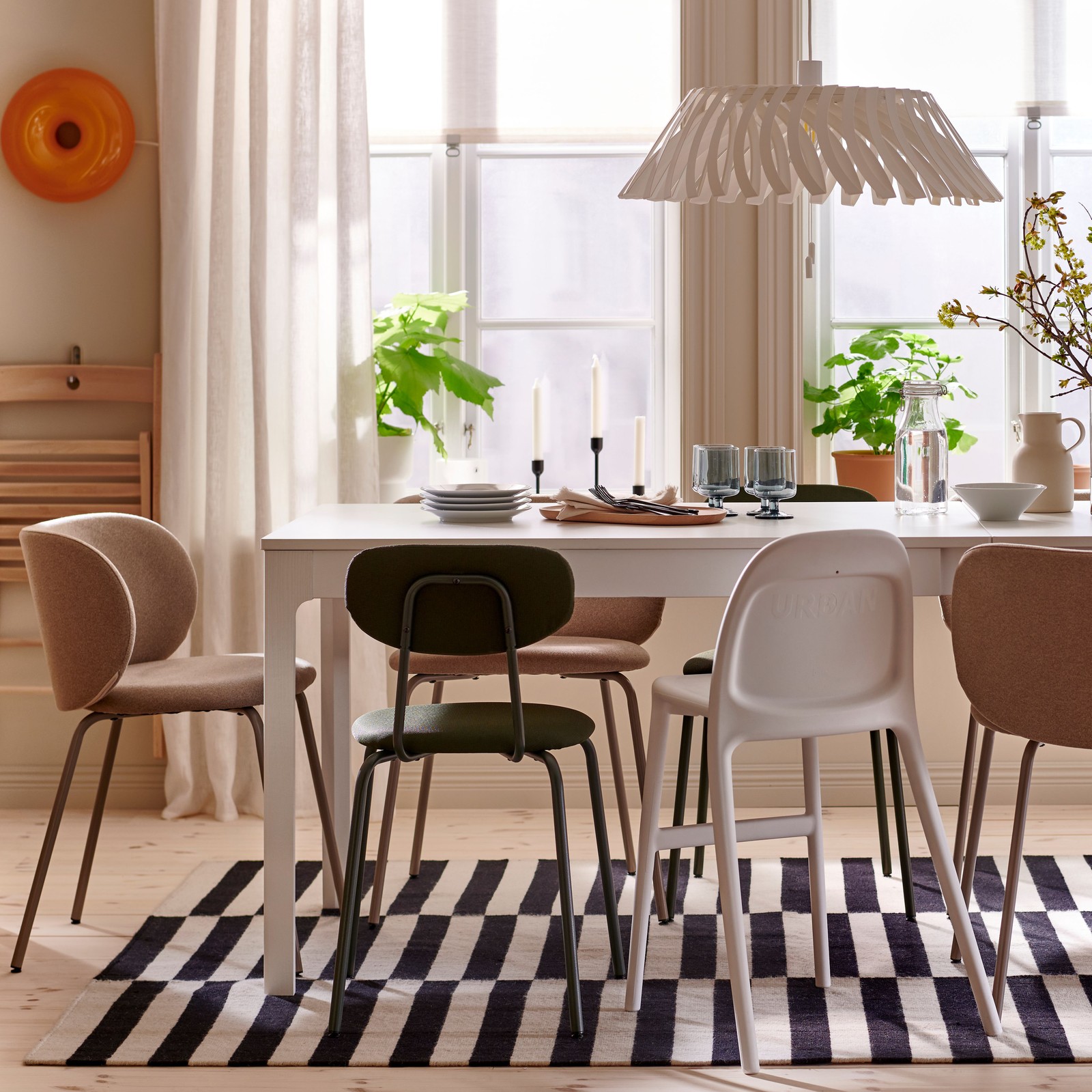 A white EKEDALEN extendable table, with different chairs around it, stands under an YTLÄGE pendant lamp in a dining room.