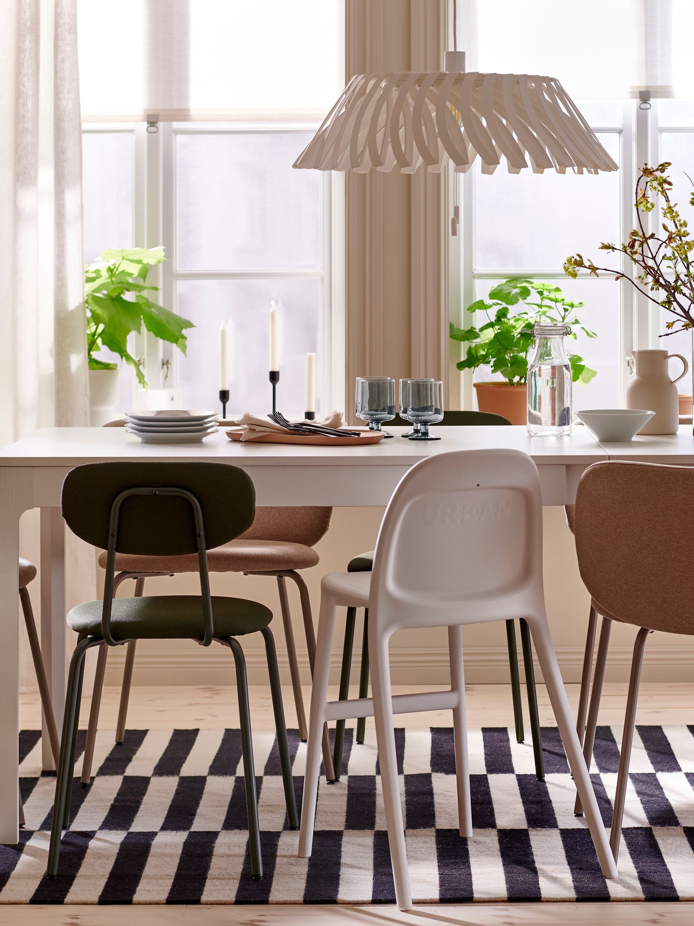 A white EKEDALEN extendable table, with different chairs around it, stands under an YTLÄGE pendant lamp in a dining room.
