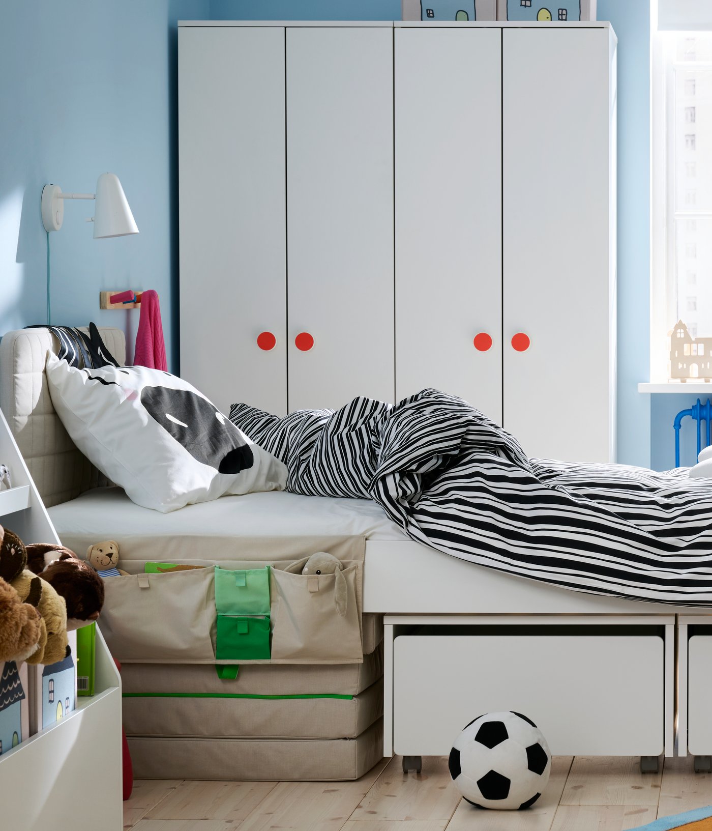 Una cameretta con il letto SLÄKT al centro e biancheria da letto NATTHÄGER. Sullo sfondo, ci sono alcuni guardaroba e una finestra.
