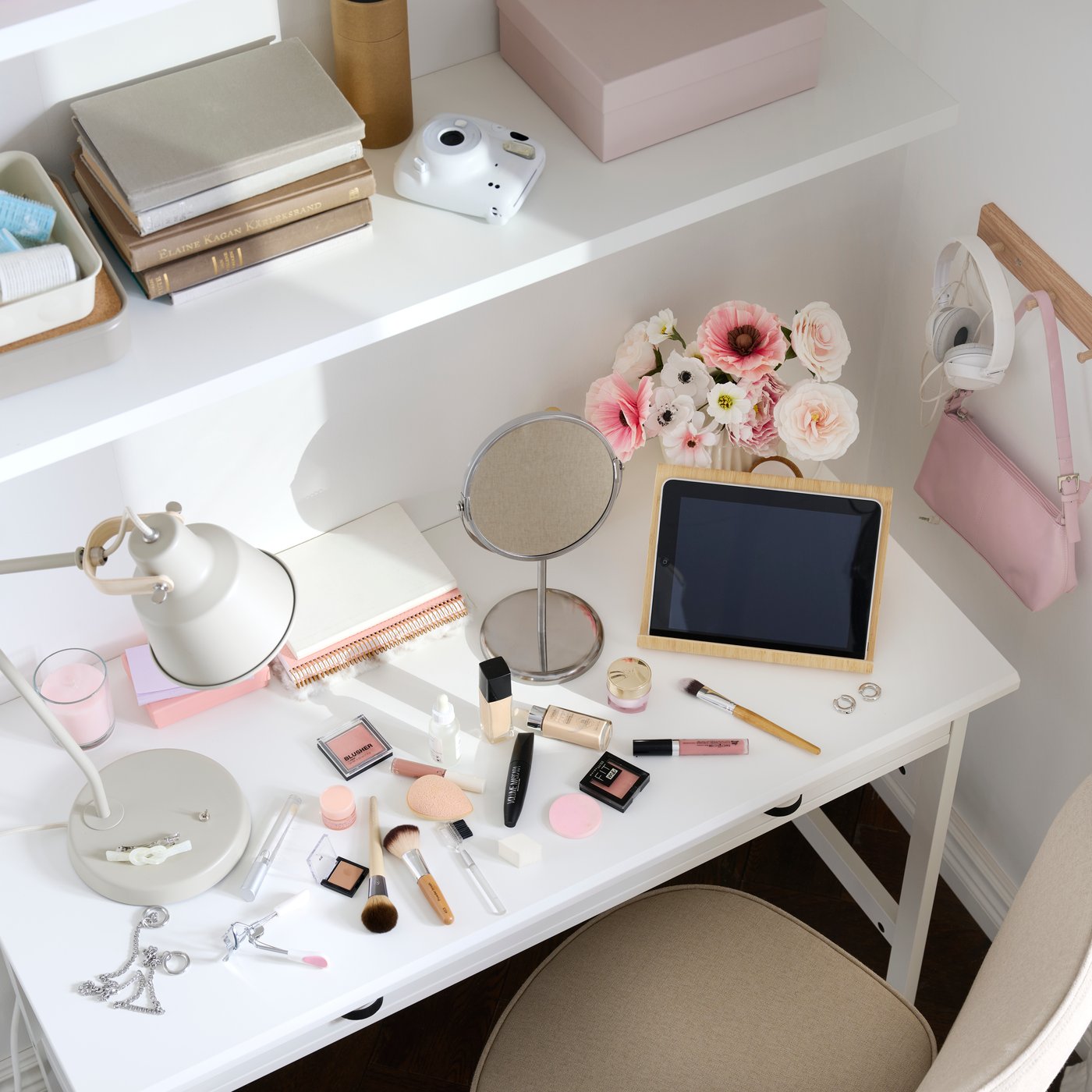 A study area with a white BRYTNING desk made from white material holds cosmetics and a tablet surrounded by flowers.