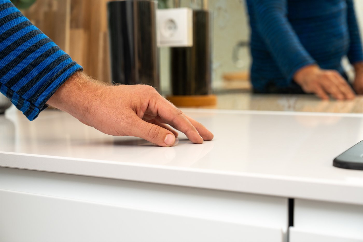 Man sieht eine Hand des IKEA Mitarbeiters wie sie auf der Arbeitsfläche der weißen IKEA Küche liegt.