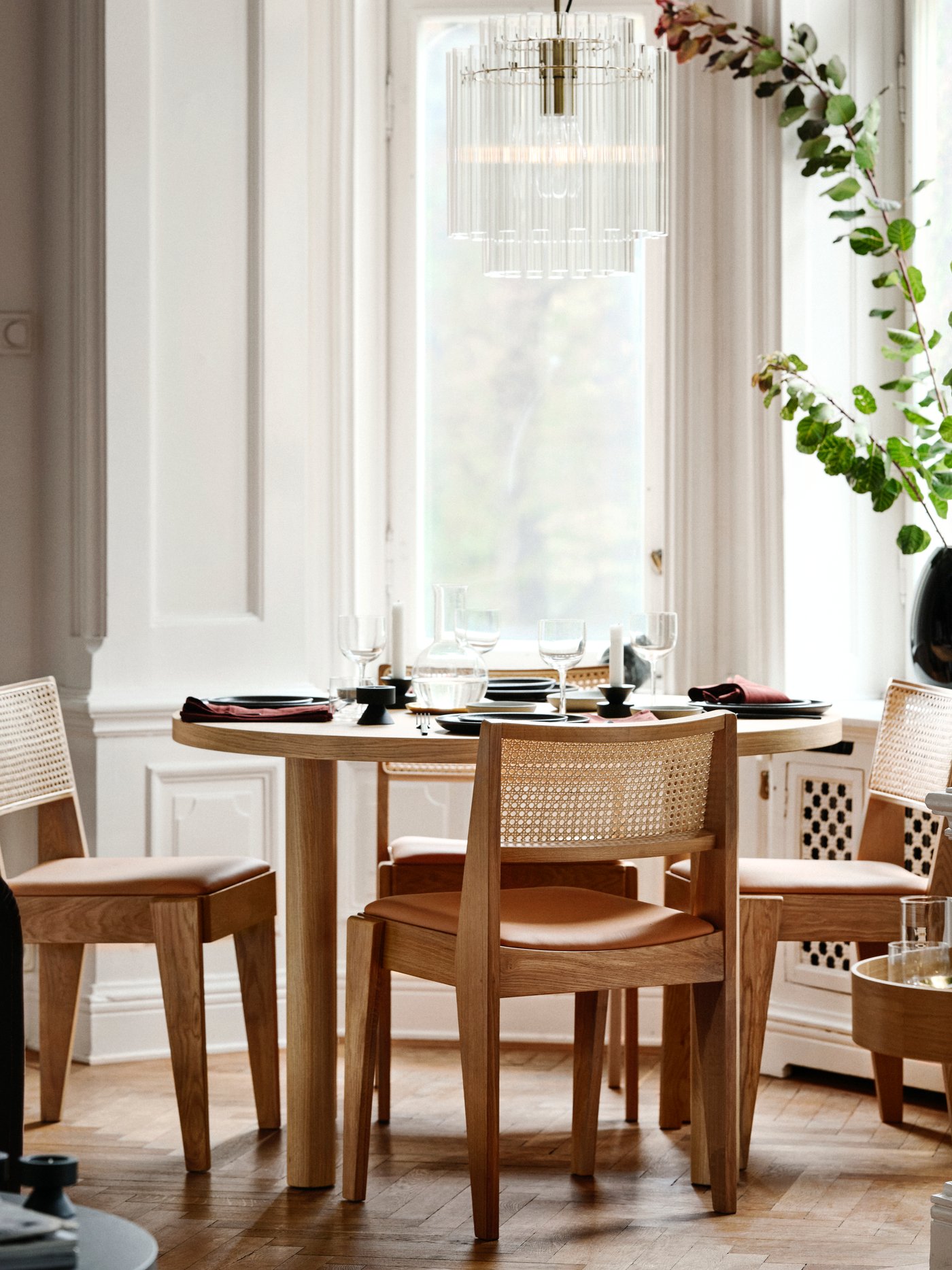 Suuren ikkunan edessä on STOCKHOLM-pöytä, jonka ympärillä on sarjan rottinkiselkäisiä tuoleja.