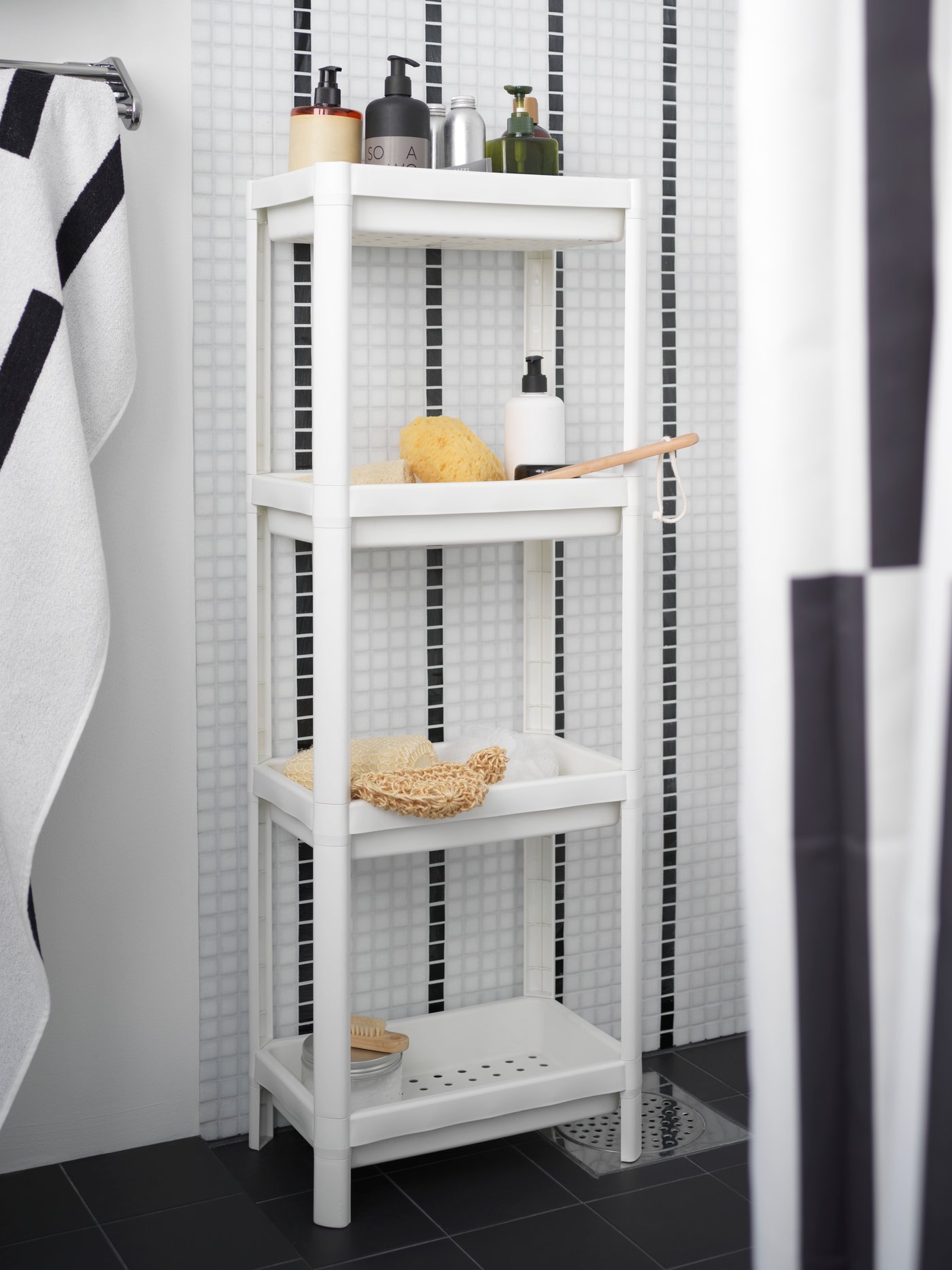 Un estante de baño VESKEN con cremas y otros artículos en su onterior. Al costado una toalla colgada en la pared.