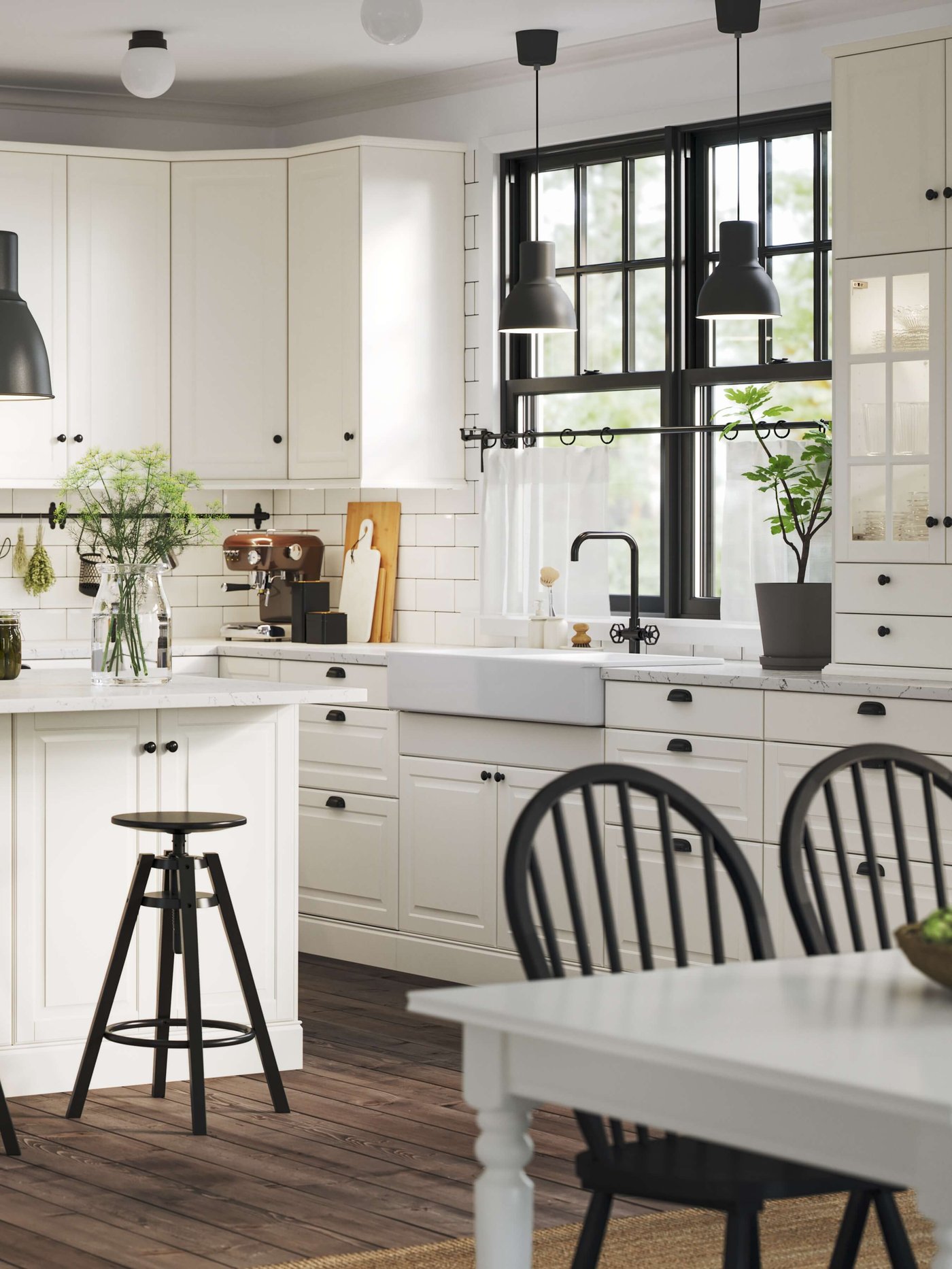 Bright white kitchen with black-framed windows, farmhouse sink, island stool, pendant lights.