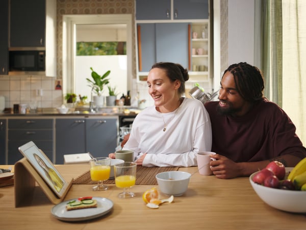 Two people sitting in their kitchen taking a call remotely with an IKEA co-worker on their tablet.