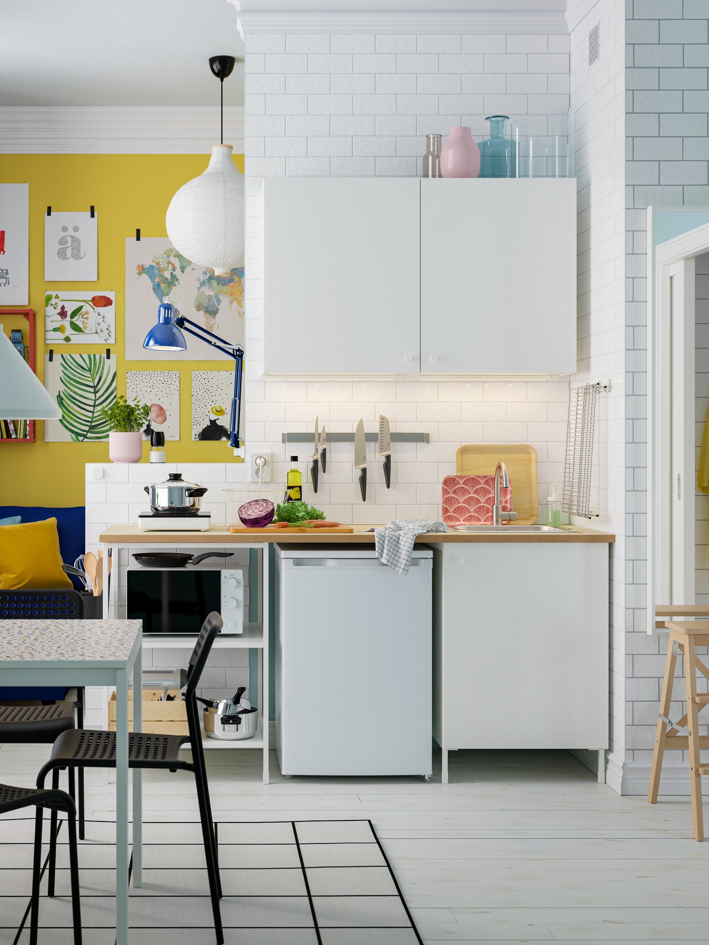 Eine kleine, helle Küche mit einer weißen ENHET Küchenkombination, einem weißen Esstisch und vier schwarzen Stühlen.