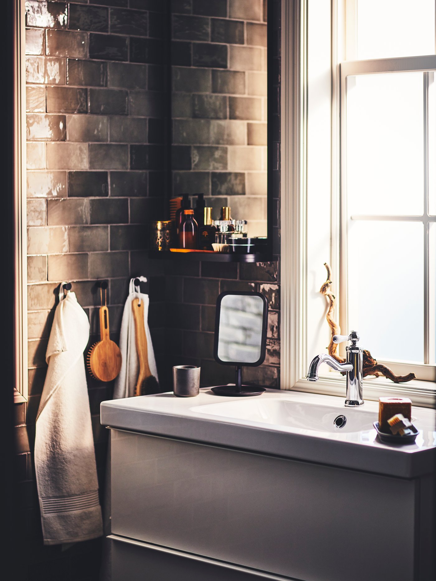 A bathroom with a GODMORGON wash-stand with two drawers, a black LINDBYN table mirror and items hung from SKOGSVIKEN hooks.