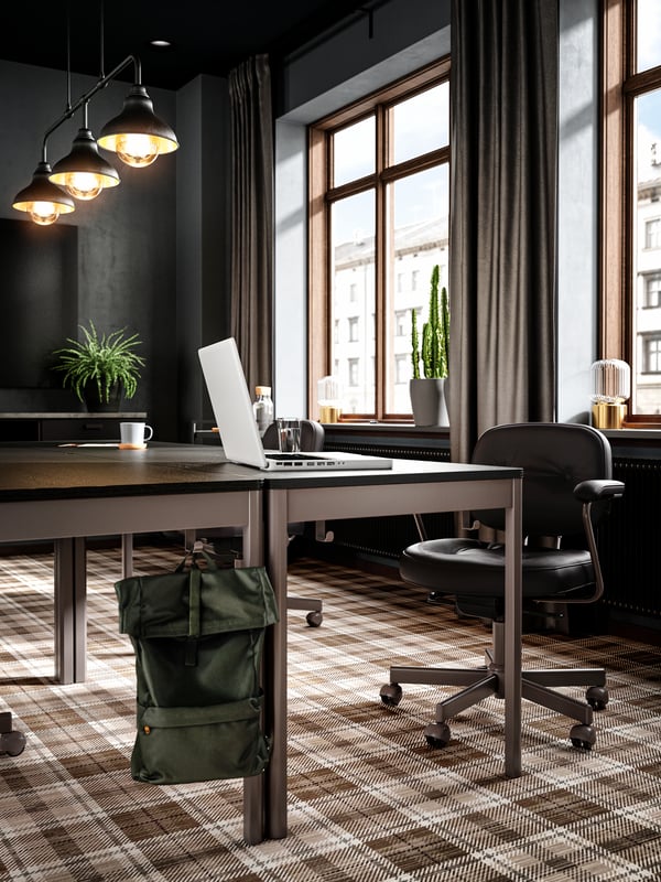Tables put together to form a conference table, black leather conference chairs, a white laptop on the table.