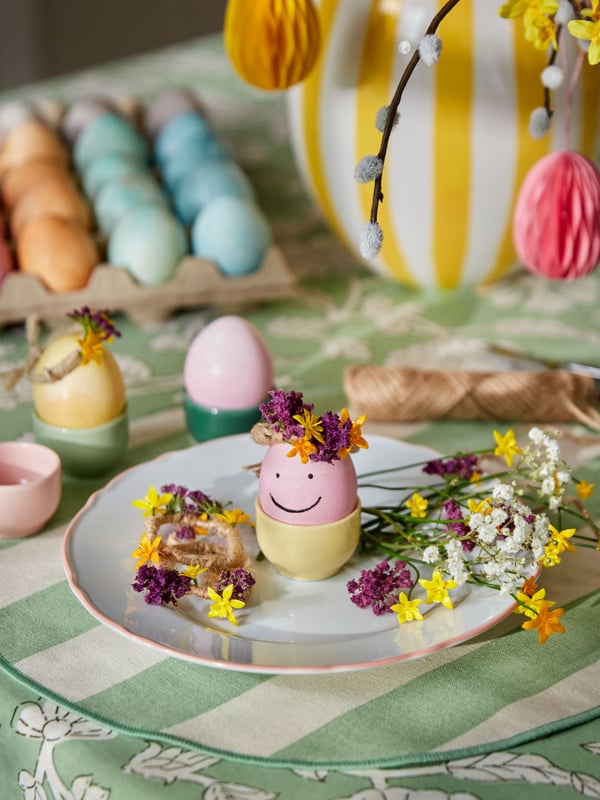 Close-up of pastel Easter eggs styled on a plate with spring flowers and greenery.