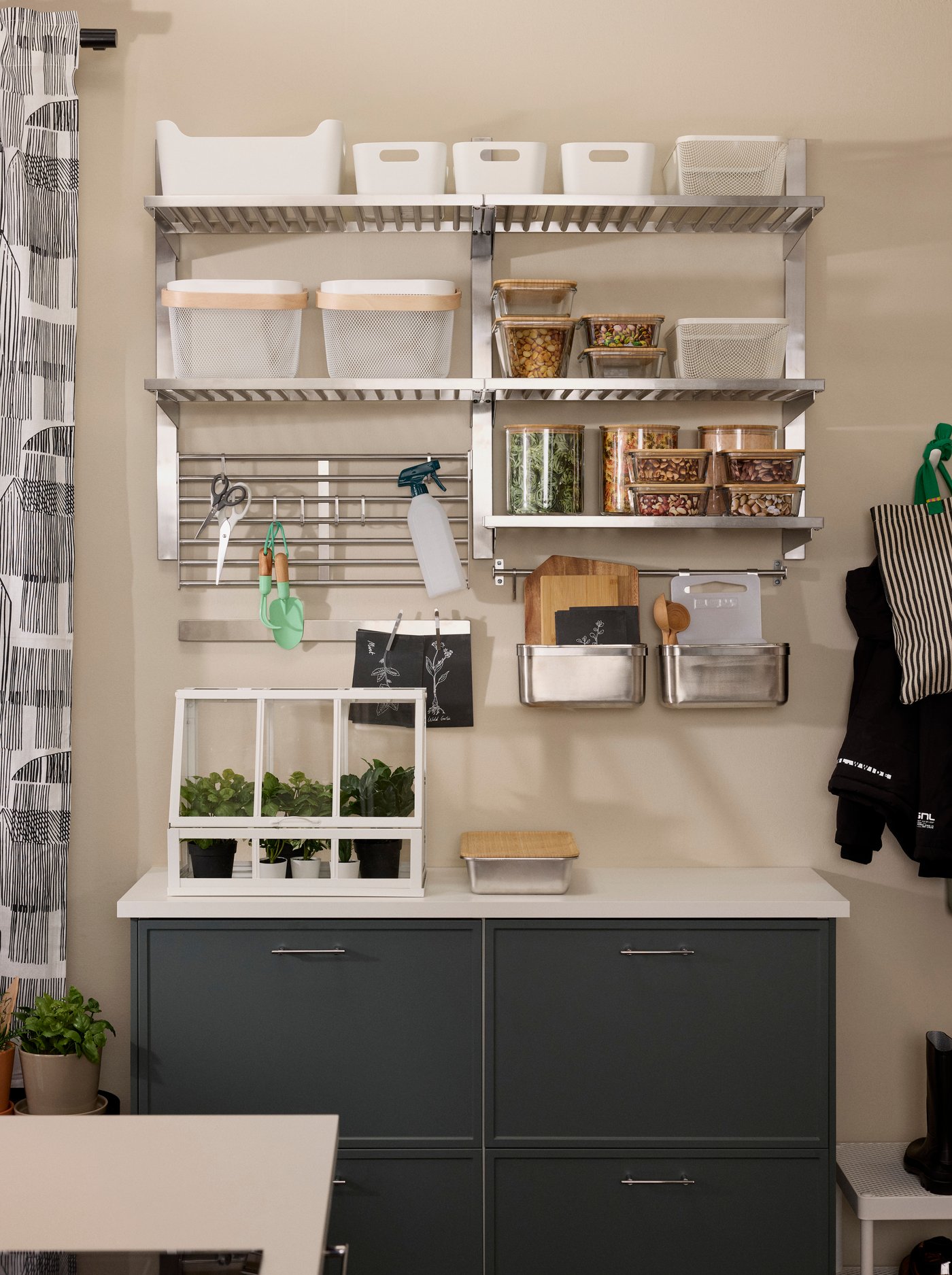 Open wall storage solution in the kitchen with metal shelves and accessories holding food containers, baskets and kitchen utensils.