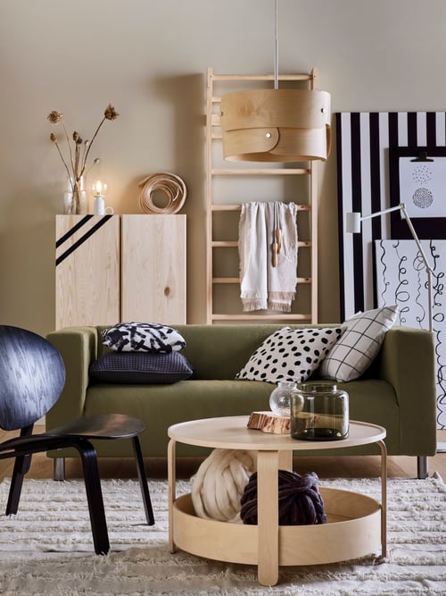 Modern living room with sofa, easy chair, and coffee table holding an elegant green-brown vase made of mouth-blown glass.