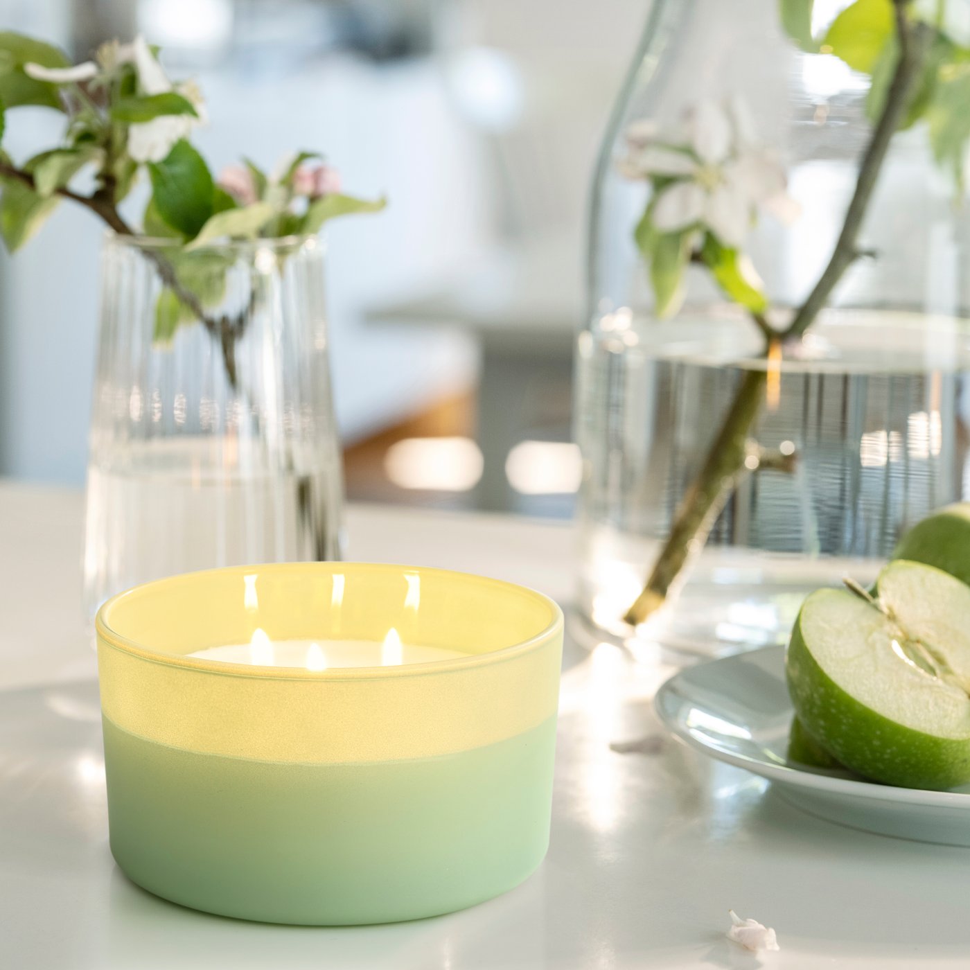 Ett LÖVSKOGSLUND doftljus står på ett bord tillsammans med två glasvaser.