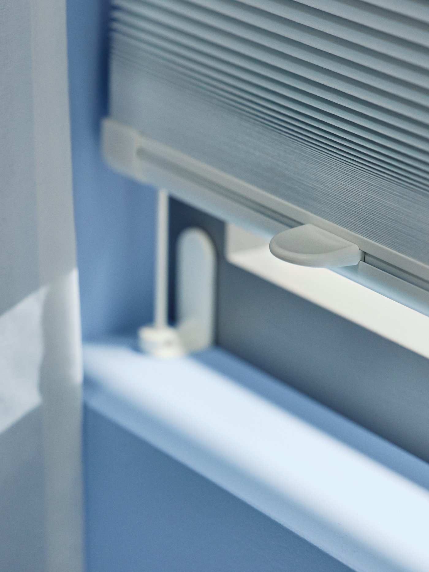 الجزء الأسفل من ستارة معتمة بطيات HORNVALLMO مسحوبة للأسفل بالكامل على نافذة.