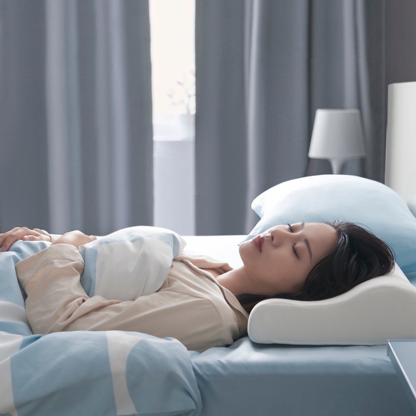 A woman sleeping on KLUBBSPORRE cooling pillow in bedroom