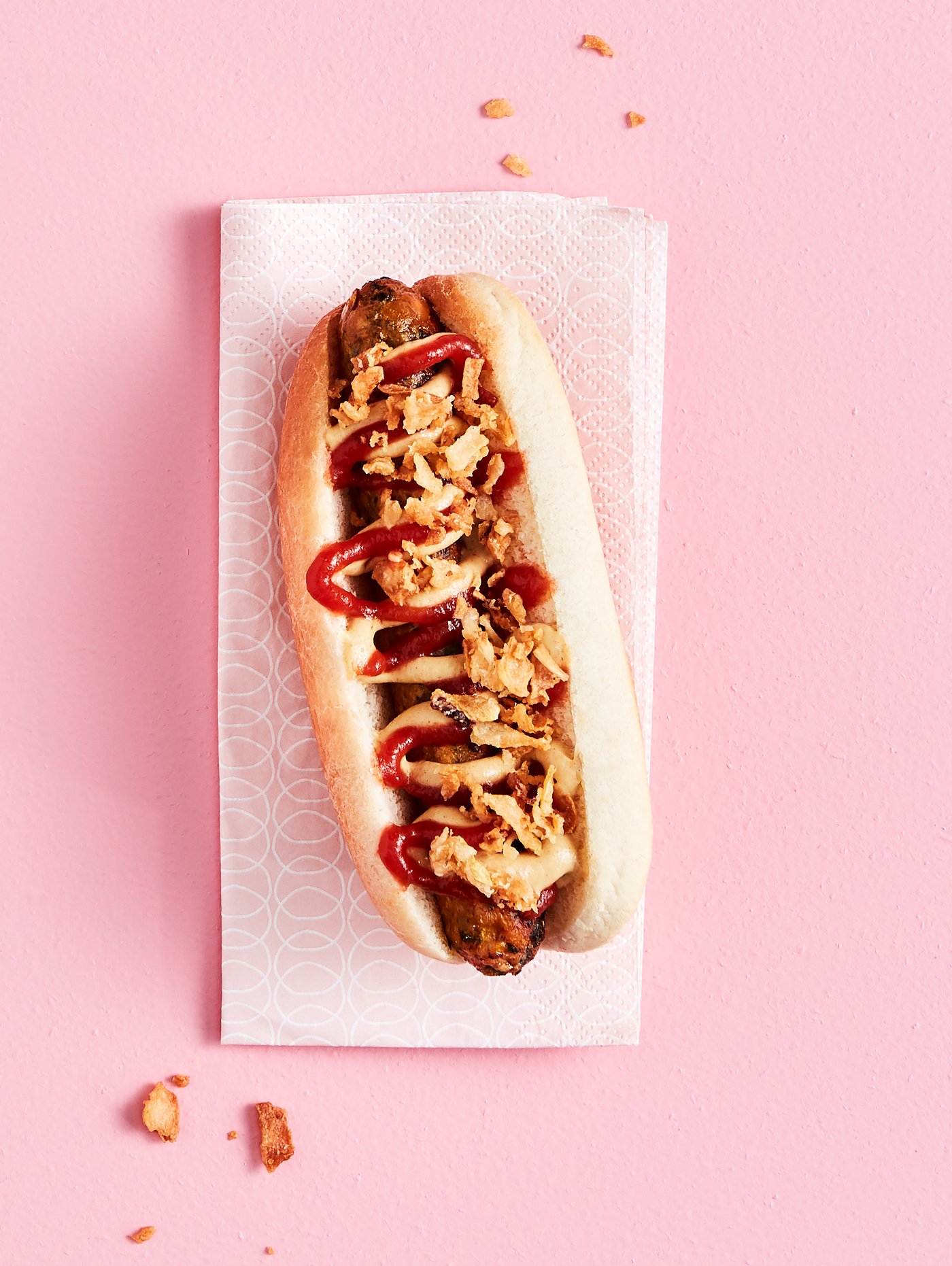 A KORVMOJ vegetable hotdog with ROSTAD LÖK fried onions on a KORVBRÖD hotdog bread, served on a paper napkin.