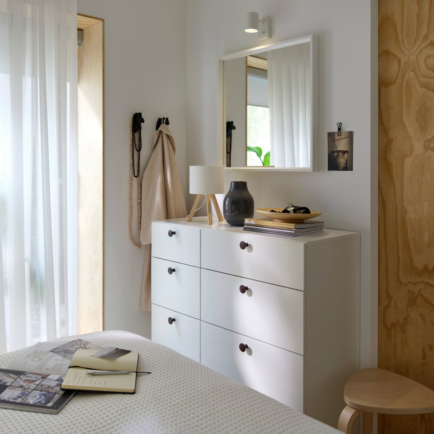 A bedroom setup with LASTARE chest of drawers placed below a wall mirror and decorated with various items.