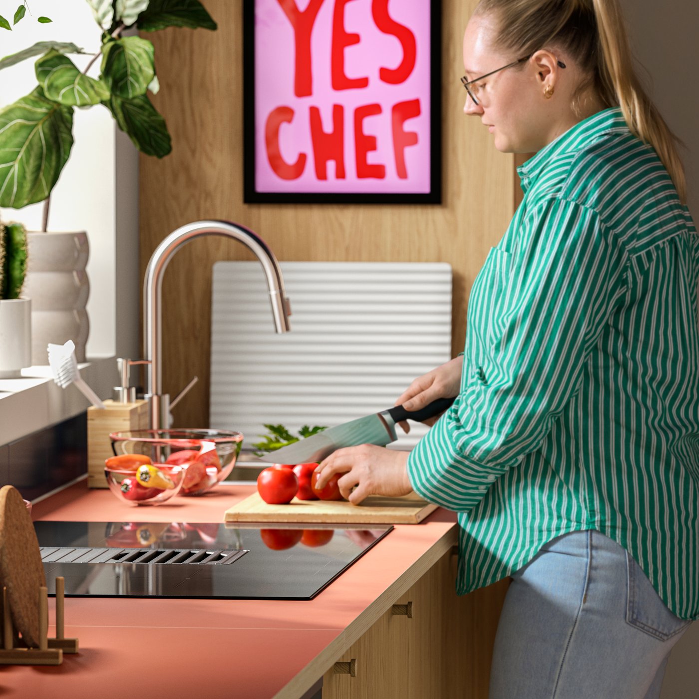 A person is chopping tomatoes on a chopping board next to a FÖRNEBO induction hob with integrated extractor.
