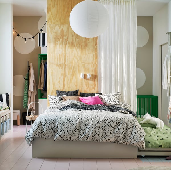 A VIHALS bed with 2 storage boxes and 1 trundle bed covered with black and white BJÖRKGRÅMAL bed linen in a light bedroom.