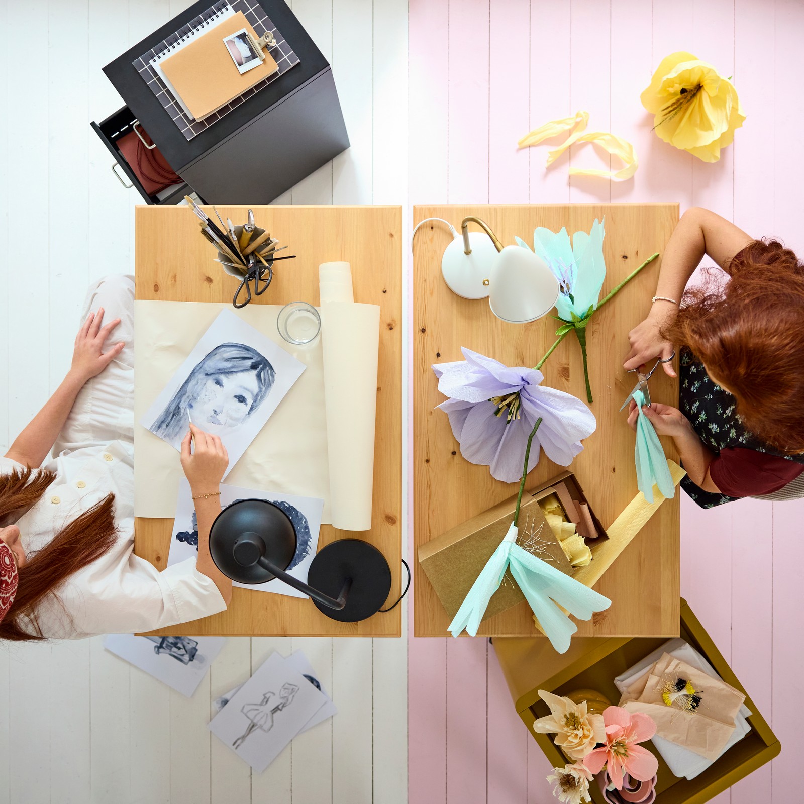 Two BOLLPOJKE desks in pine/white side by side, viewed from above, with two teens crafting and using art supplies.